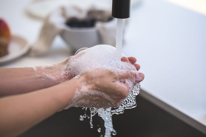 Soapy hands being rinsed under running water