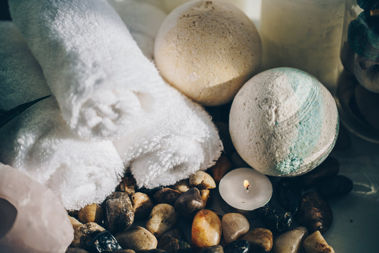 A folded towel, candle and smooth stones arranged for a bath