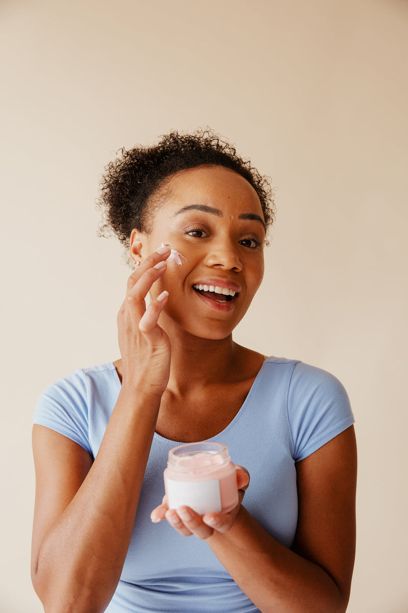 A woman applying skincare in front of a mirror