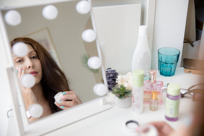 A person looking into a mirror while rubbing in face cream