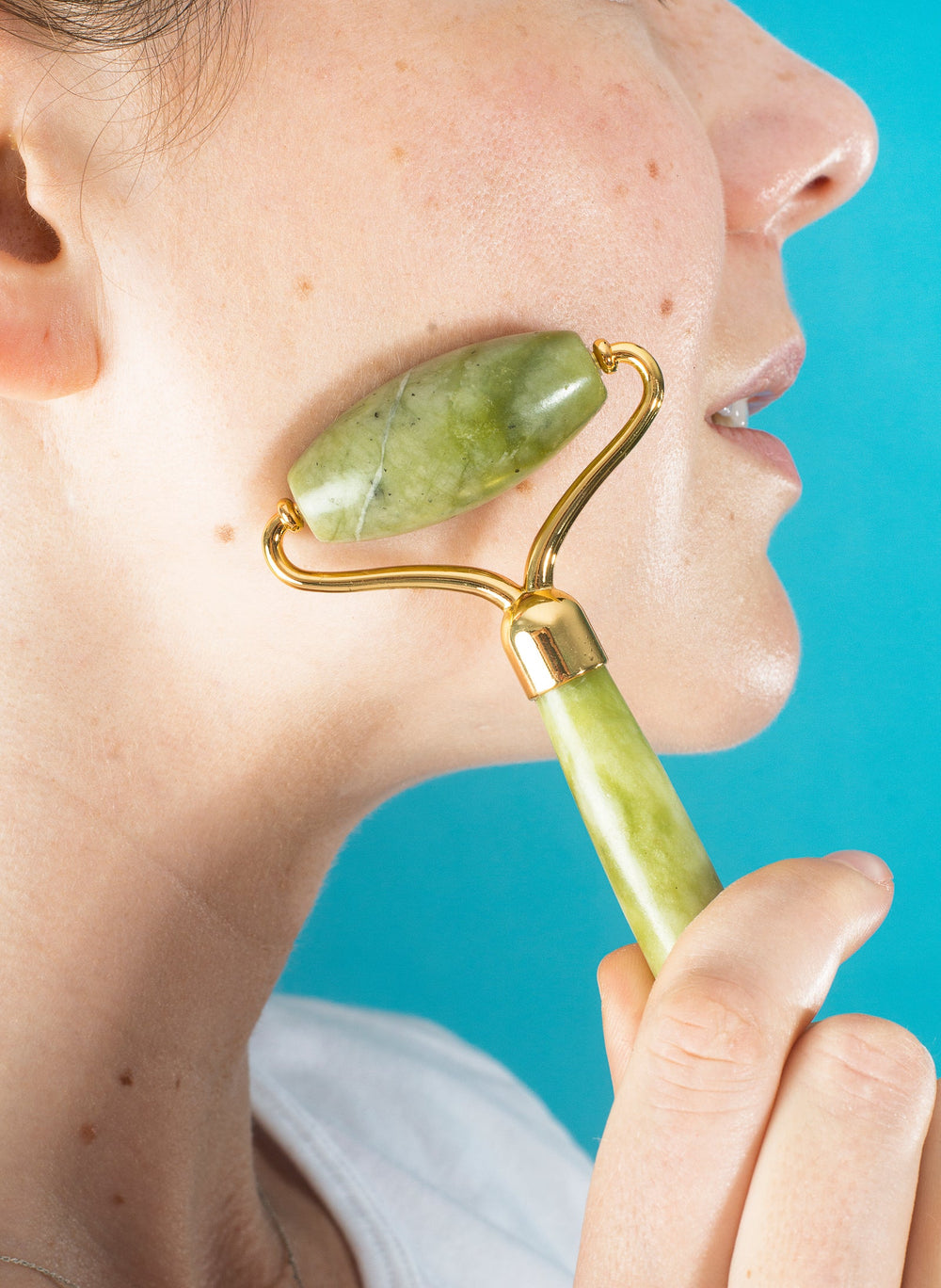 Close-up of a jade roller being used on the cheek