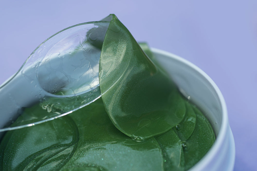 An open jar of green hydrogel under-eye patches