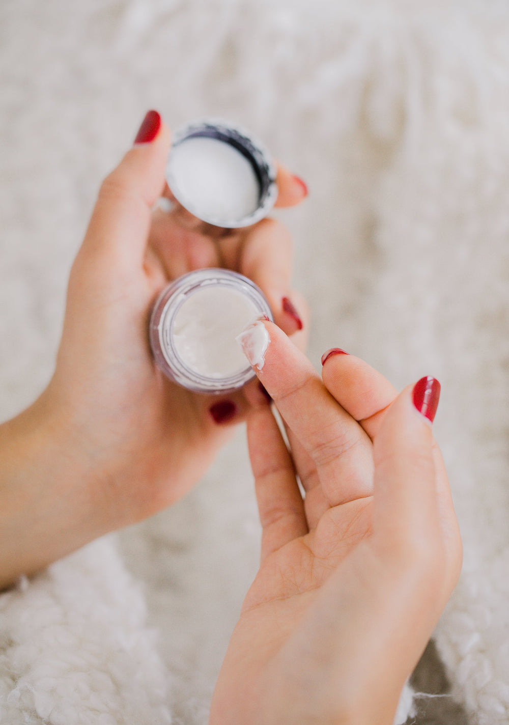 Hands holding a small white cosmetics container