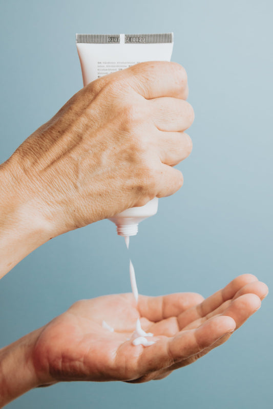 Hands squeezing cream from a tube of hand cream