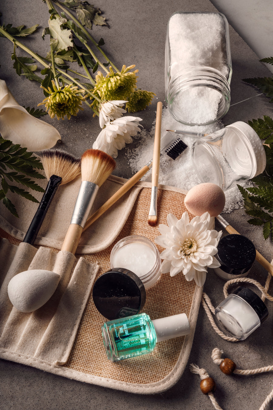 A flatlay of beauty products on a pale surface