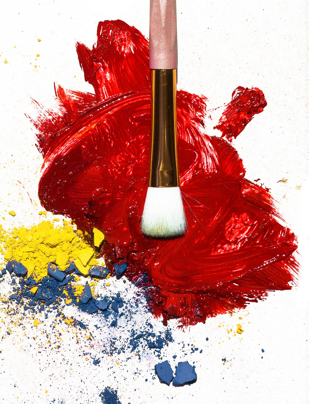 A makeup brush resting on a swatch of vibrant colour