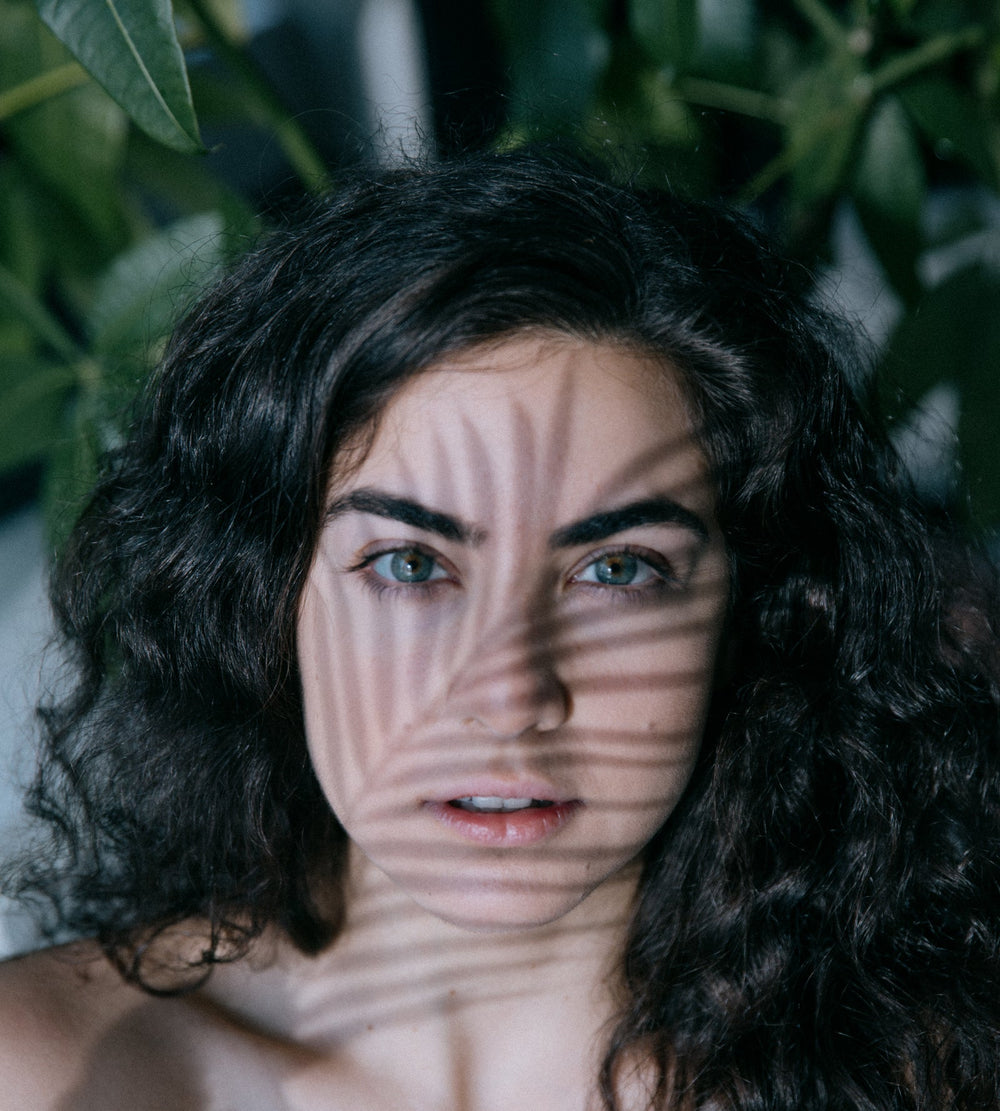 A person in sunlight with the shadow of a leaf across their face