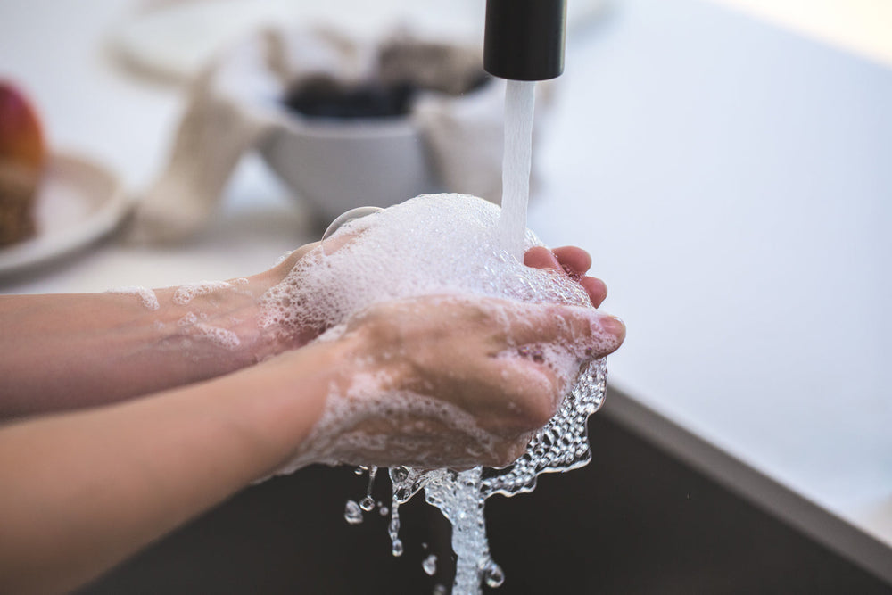 Soapy hands being rinsed under running water