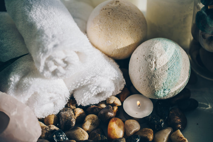 A candle, folded towel and smooth stones set out for a bath