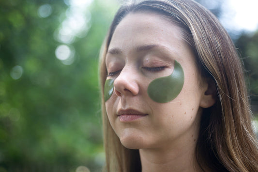 A woman outdoors with her eyes closed wearing under-eye patches
